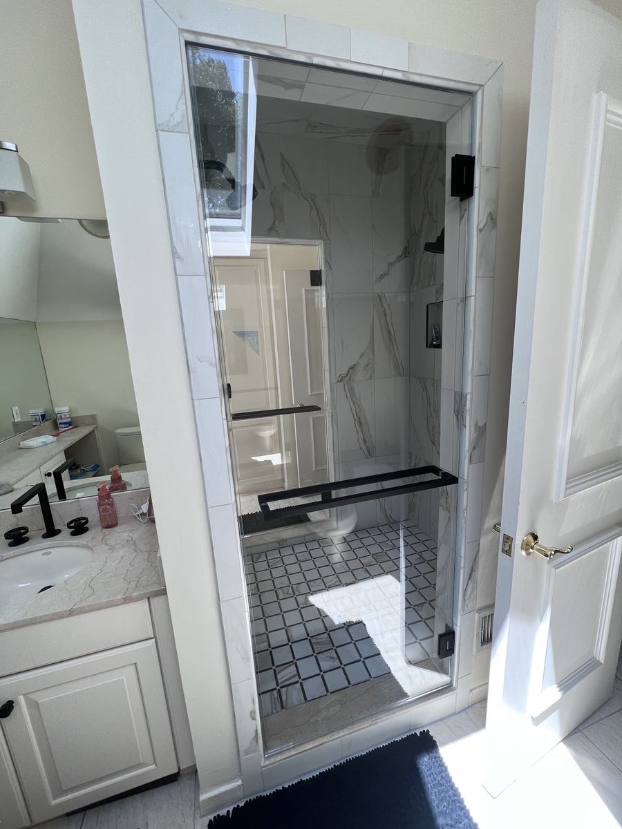 Frameless hinged shower door with matte black hardware