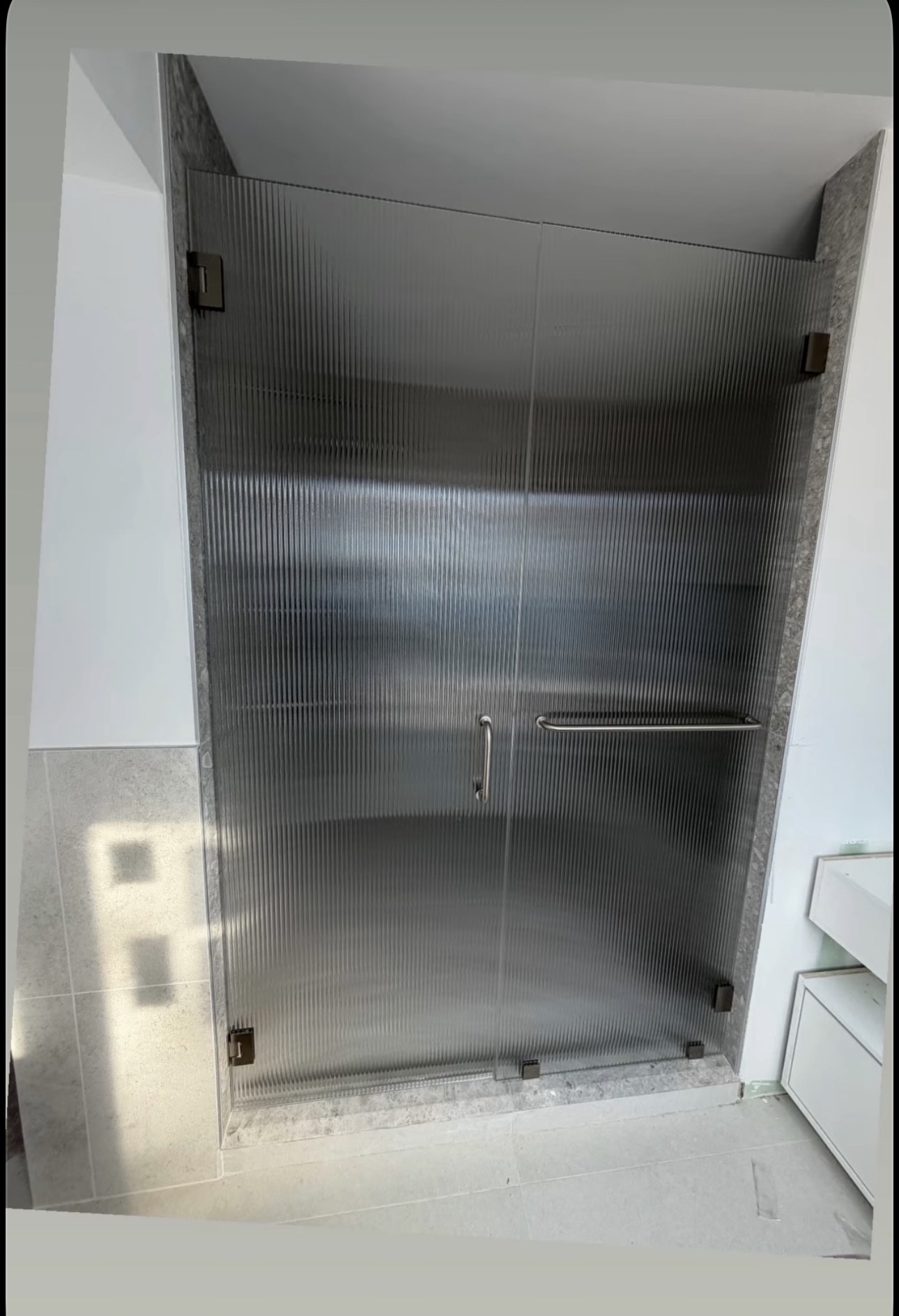 Frameless hinged shower door with reeded glass
