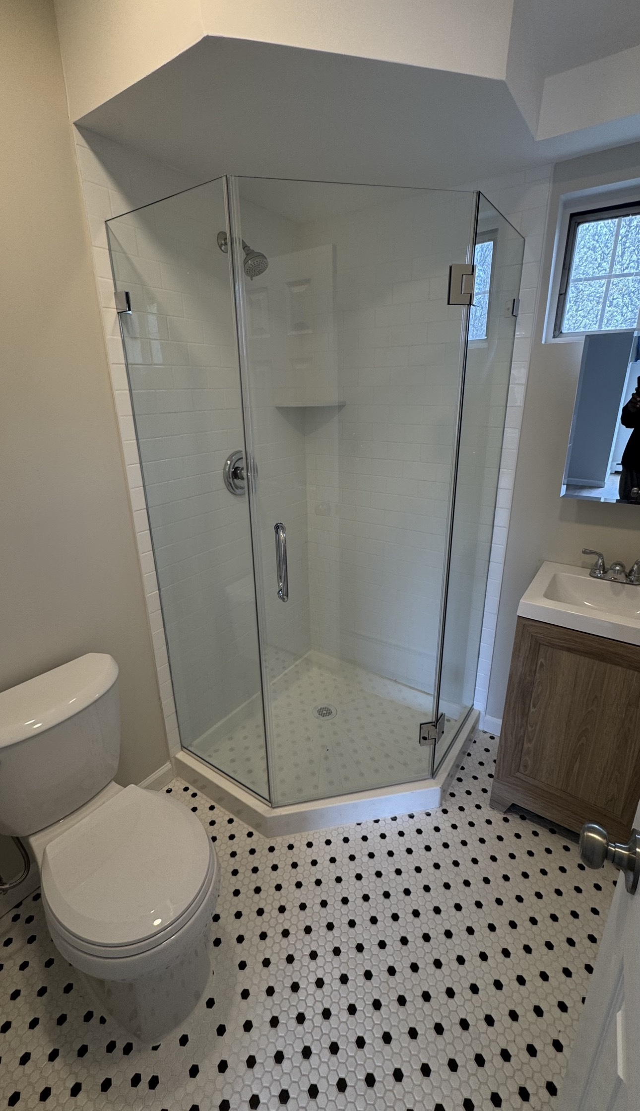 Frameless neo-angle corner shower enclosure with angled glass panels and white subway tile